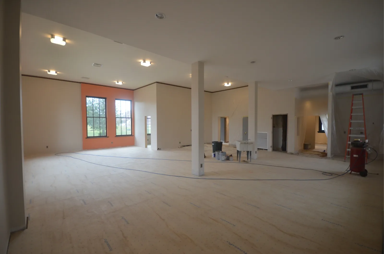 The finished open office with tall windows, an orange accent wall and new light fixtures