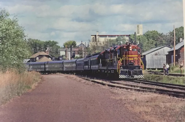 A maroon Duluth, Missabe and Iron Range diesel pulling passenger cars