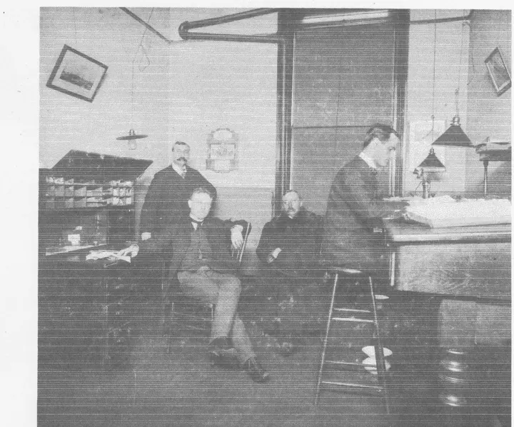 Four men in the depot office in 1901, one seated in front, one writing at a tall desk