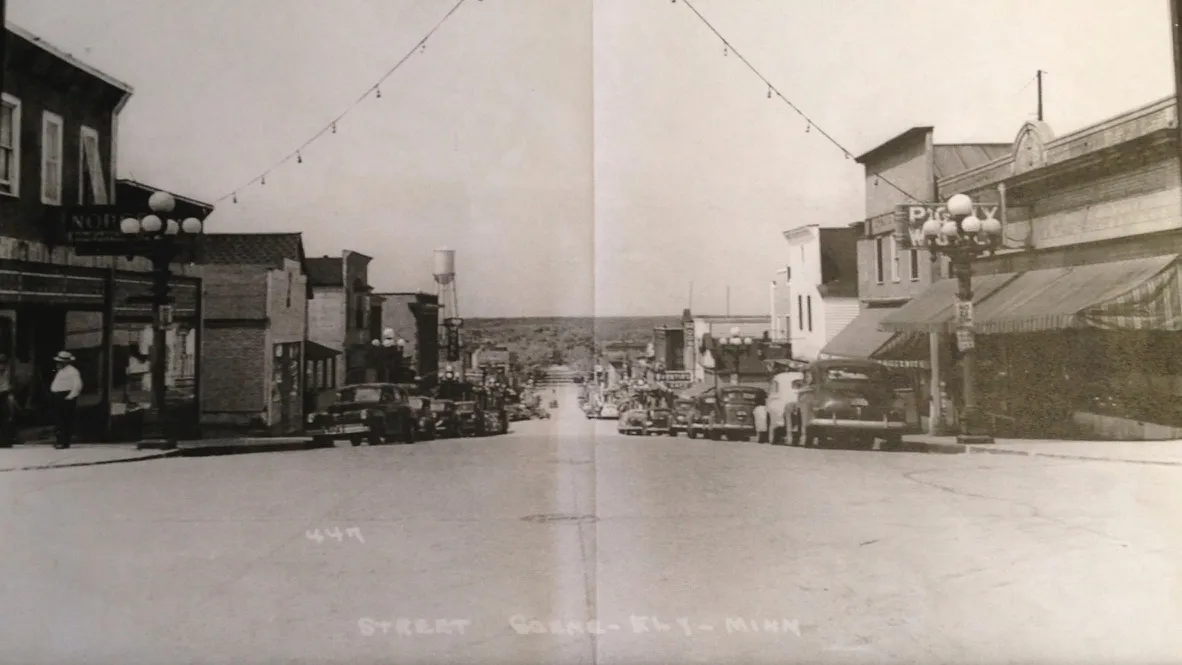 Postcard view down Sheridan Street with 1940s cars, globe street lights and the Piggly Wiggly sign at right