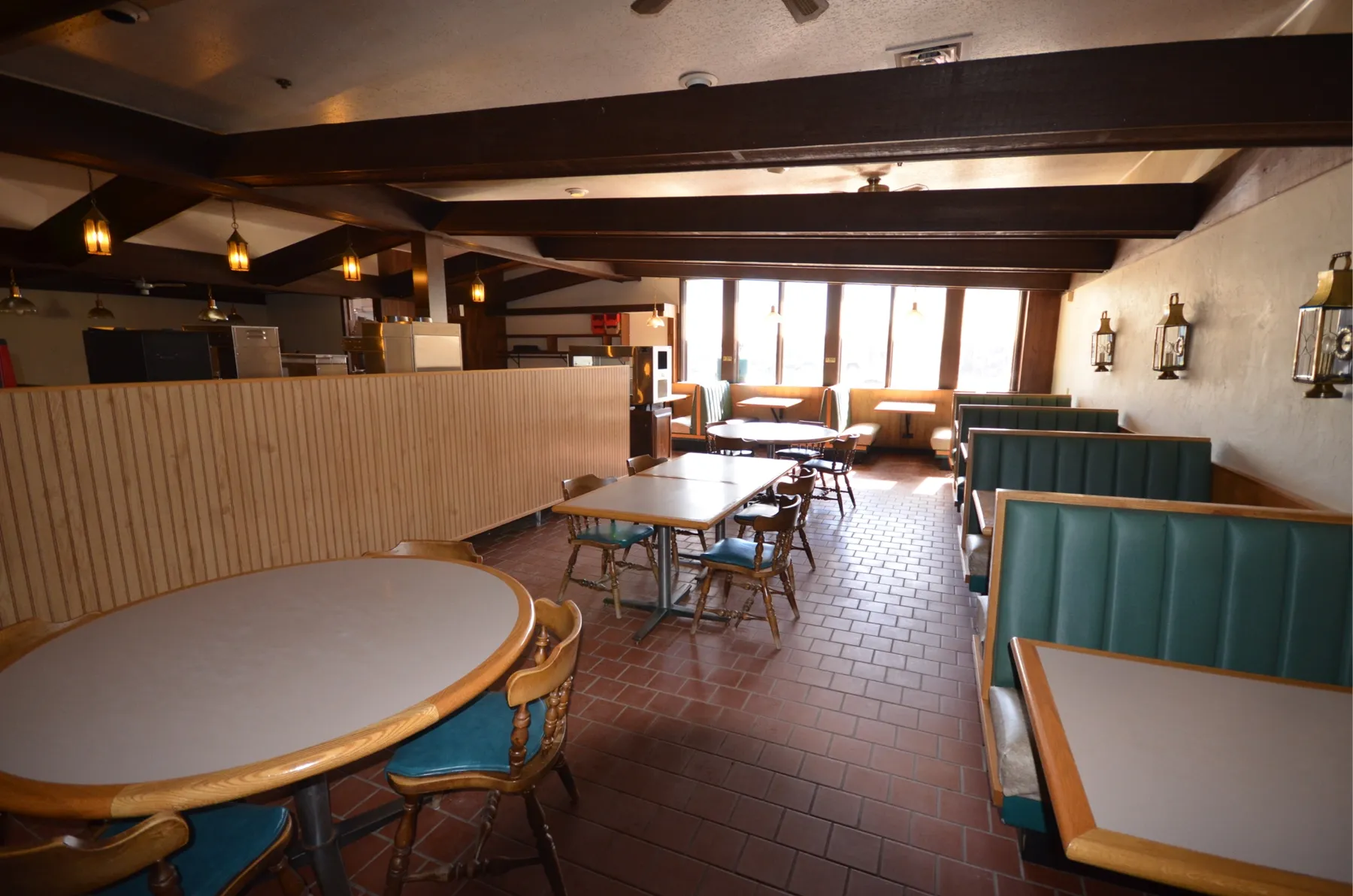 The old cafe dining room with green booths, beams and brass lanterns