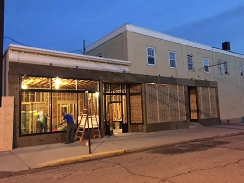 The new First Avenue storefront lit up at dusk while work continues inside