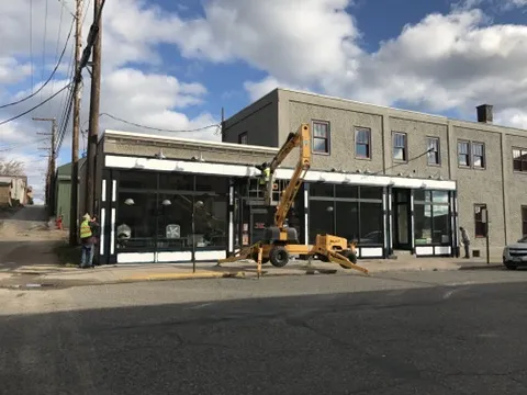 A lift parked in front of the new black storefronts on First Avenue