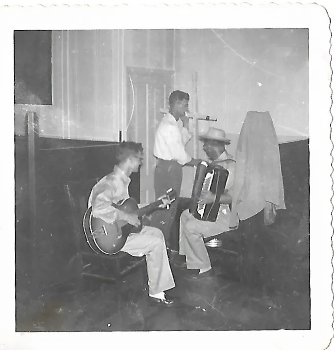 Three musicians playing guitar and accordion in the bar