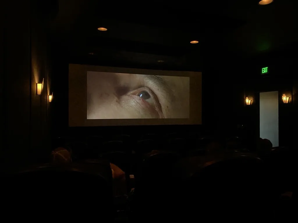 A film playing on the screen in the dark Greenstone Cinema with Art Deco wall sconces