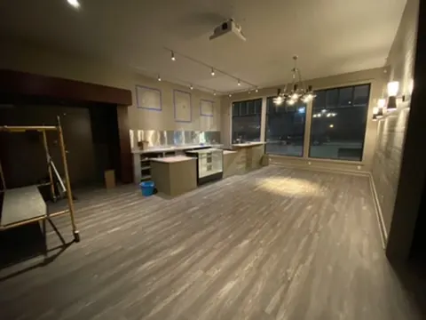 The concession lobby at night with a chandelier, wall sconces and wood-look floors