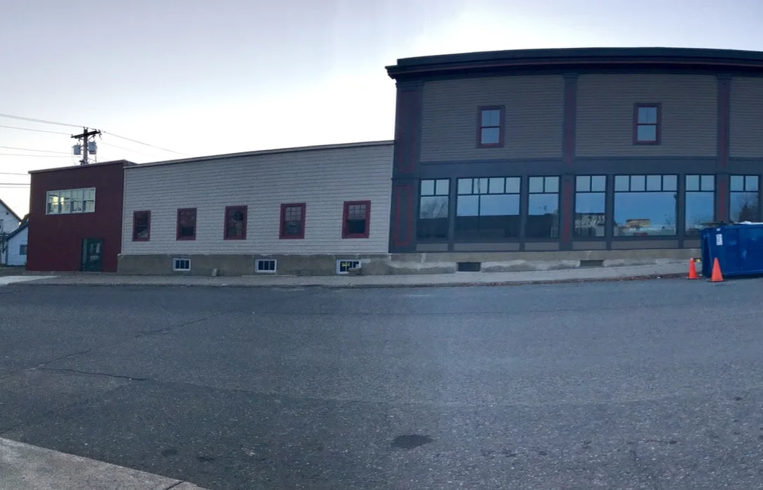 The side of the Salerno Building after renovation with new siding, red-trimmed windows and storefront glass