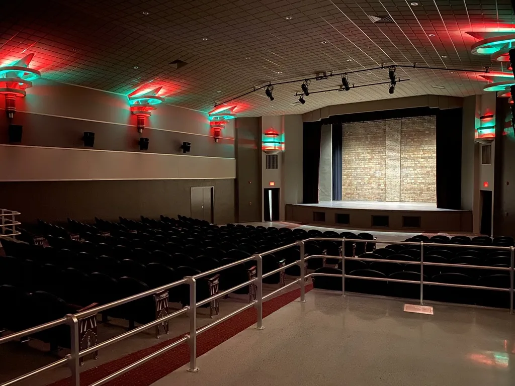The restored auditorium with red and teal Art Deco light fixtures, new seats and a stage
