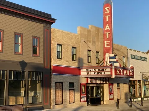 The State Theater front in evening sun with its red STATE sign and a marquee reading Movies Daily, See Website