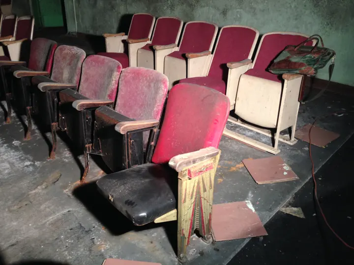 An original theater seat with a painted Art Deco end standard beside later seats