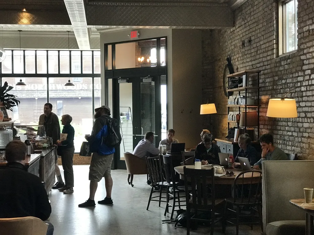 Customers at the counter and working at tables beside the exposed brick wall