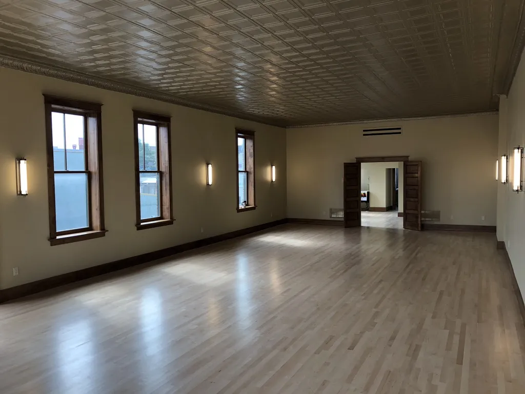 The finished upstairs hall with maple floors, tin ceiling, tall windows and wall sconces